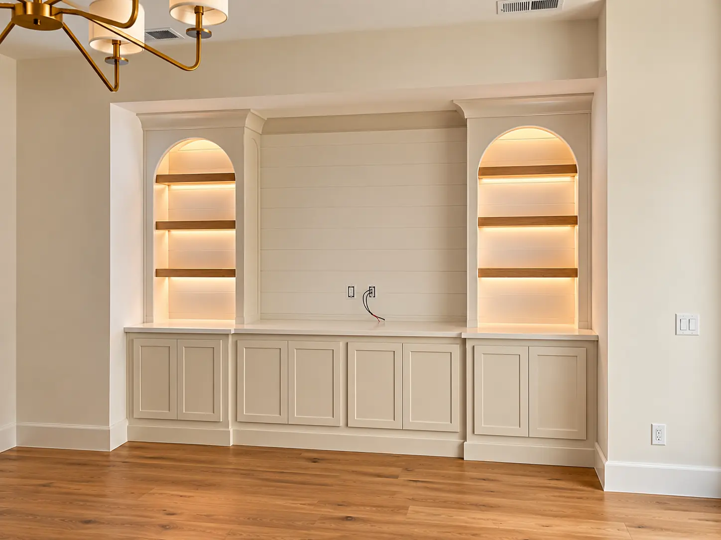 White media wall with two lit arched niches above paneled cabinets