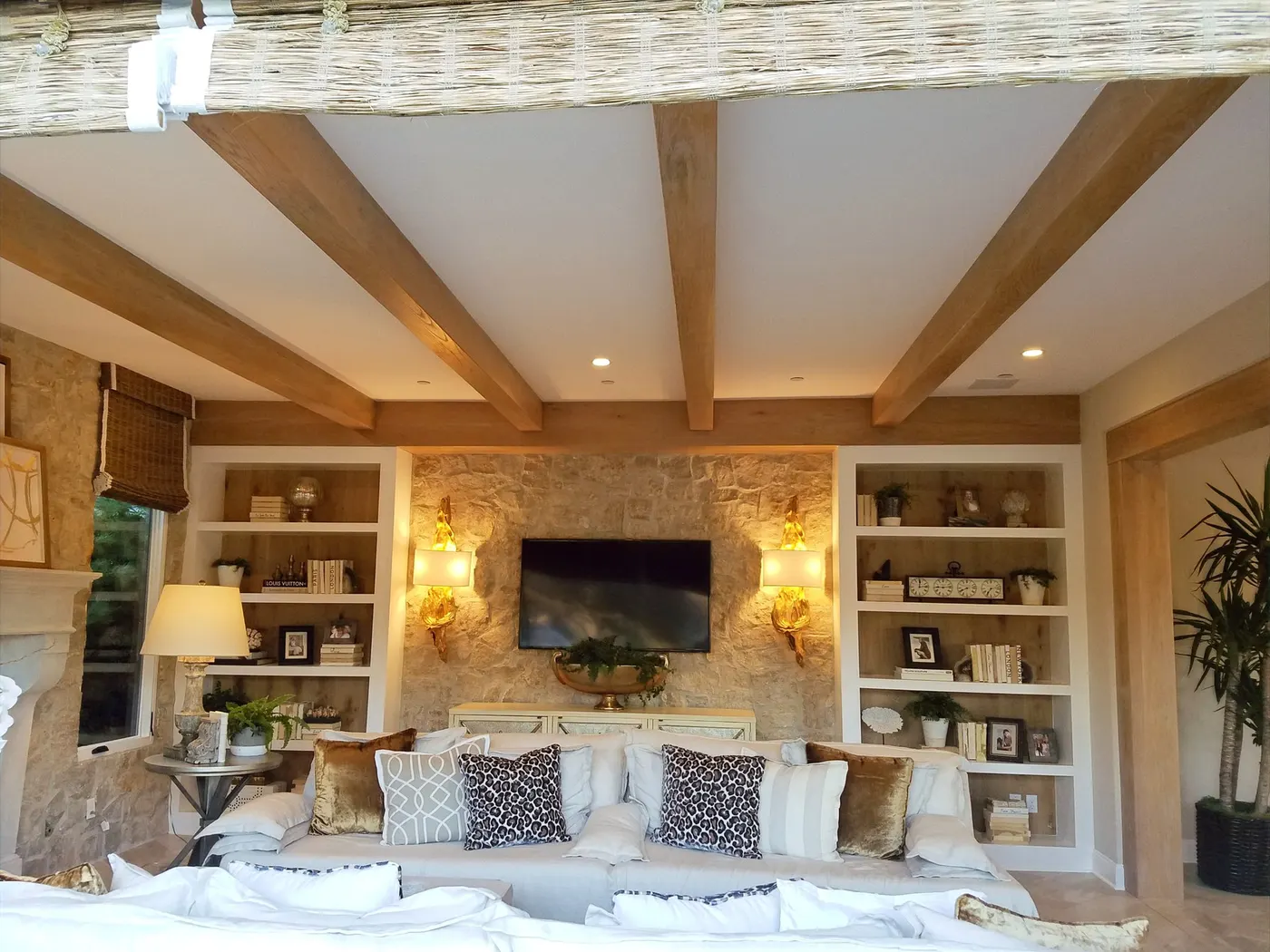 Stone fireplace with built in bookcases on both sides under wood ceiling beams