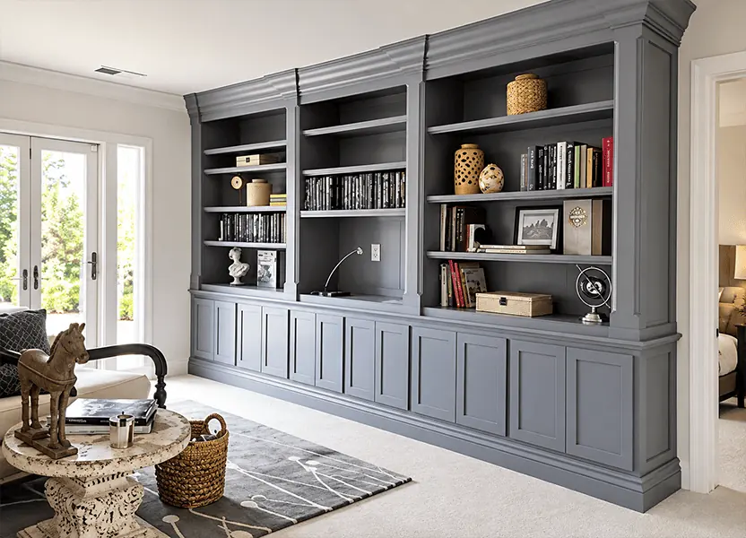 Charcoal built in bookcase wall with lit shelves and paneled cabinets