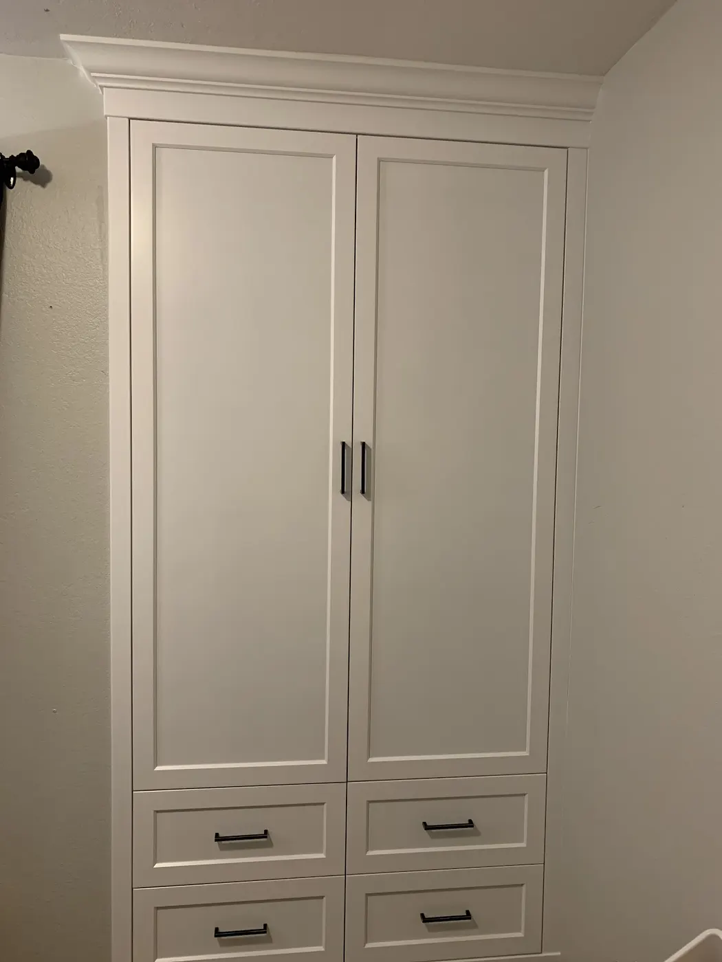 Tall white built in wardrobe with two doors over four drawers