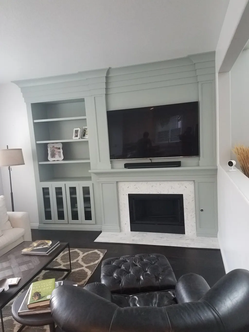 Sage green built in with a fireplace and bookcases