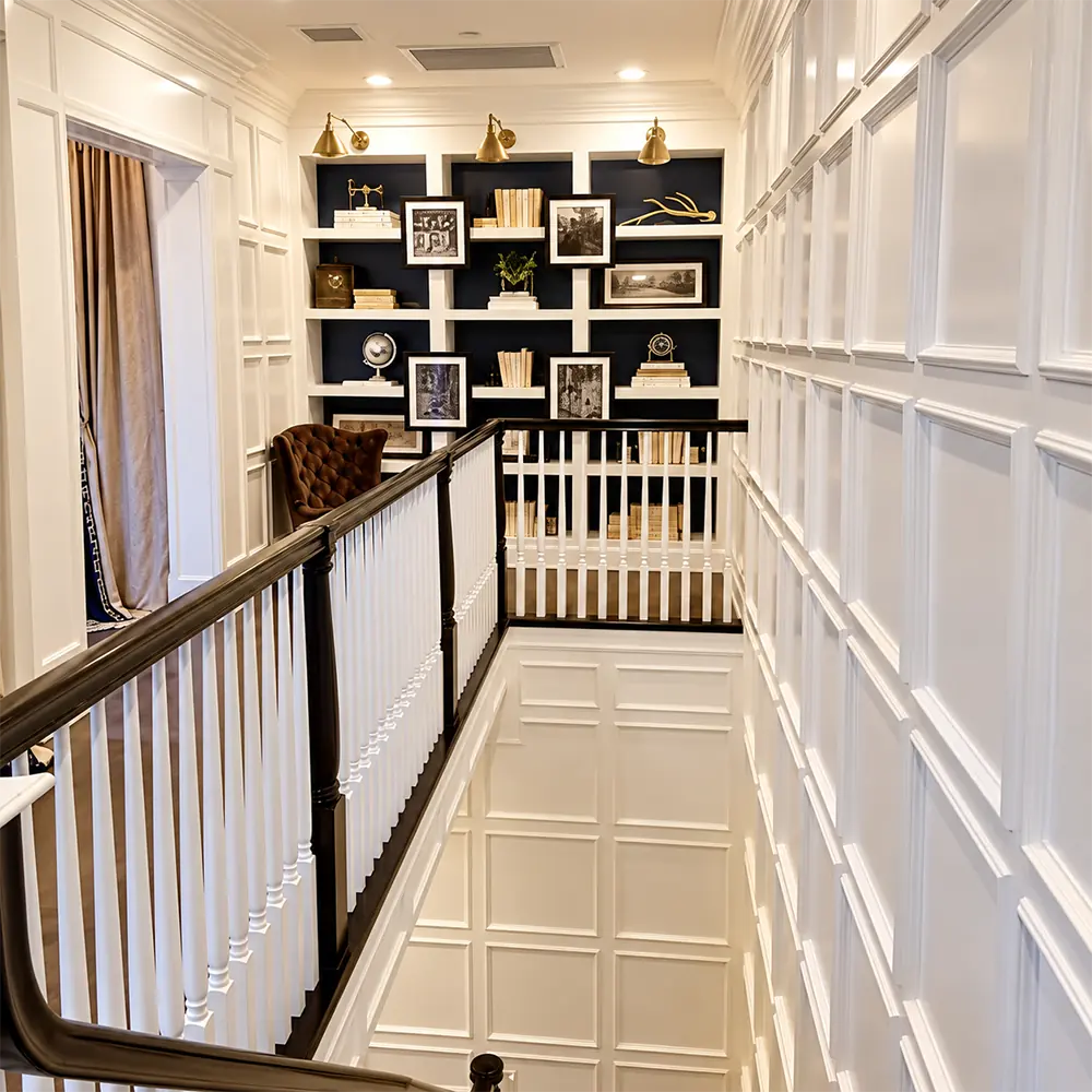 Stairwell with full height white wall paneling and a black built in bookcase